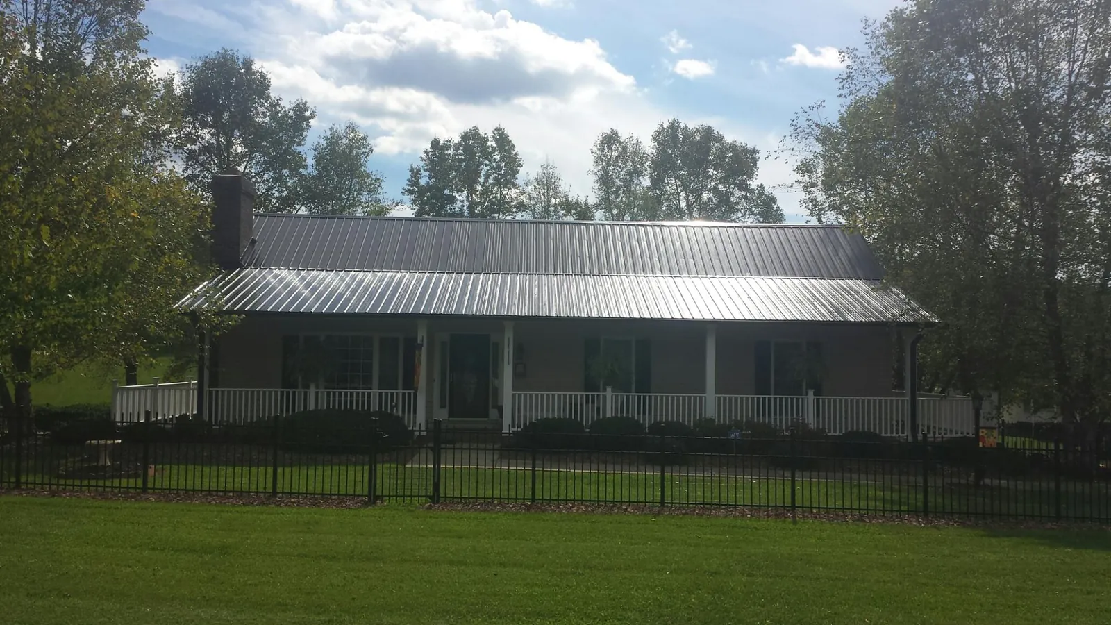 Gray metal roof on a brick ranch with a full width front porch — Gutter Guard Installation work by our crew in Mayville